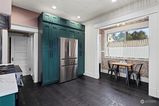 kitchen with dark wood-type flooring, freestanding refrigerator, green cabinets, wallpapered walls, and light countertops