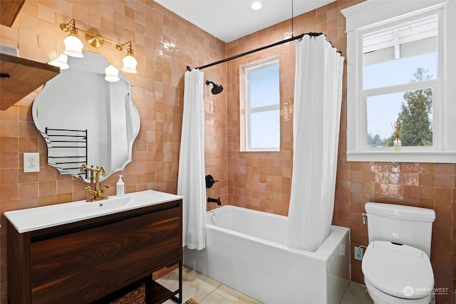 full bathroom featuring toilet, tile walls, vanity, and shower / bath combo