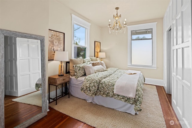 bedroom featuring a notable chandelier, multiple windows, and dark wood-type flooring