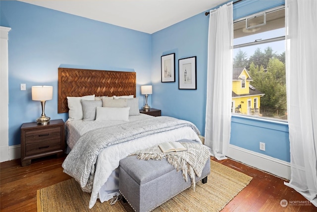 bedroom with baseboards, multiple windows, and hardwood / wood-style flooring