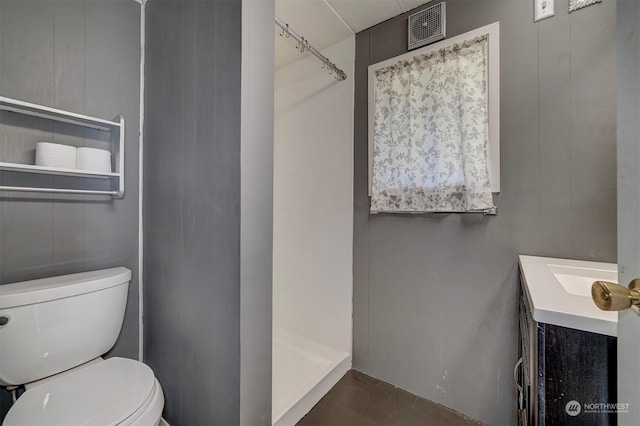 bathroom featuring vanity, a shower, and toilet