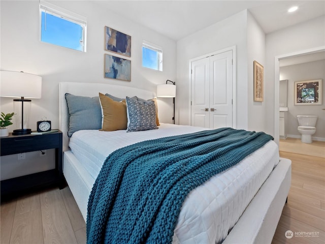 bedroom featuring ensuite bath, light hardwood / wood-style floors, and a closet