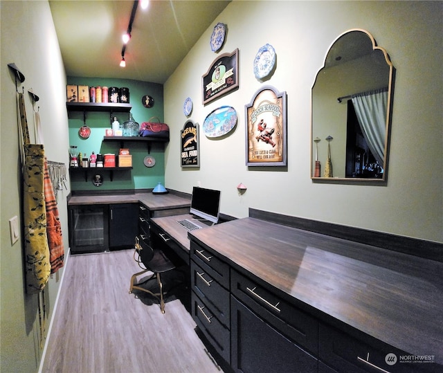 office featuring light hardwood / wood-style flooring, track lighting, and bar area