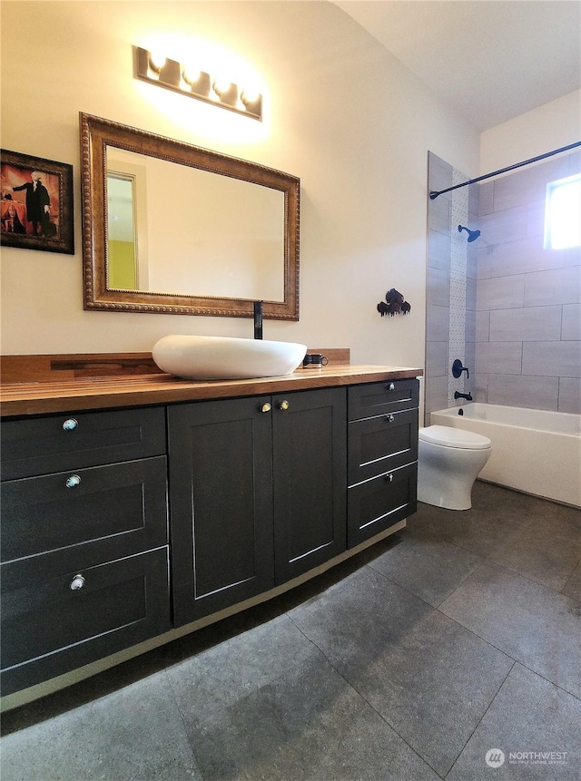 full bathroom featuring vanity, tiled shower / bath, and toilet