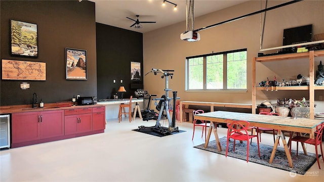 recreation room with concrete floors, track lighting, wet bar, ceiling fan, and beverage cooler