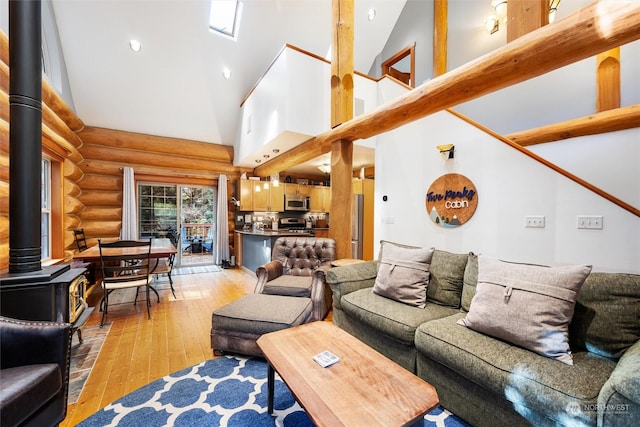 living room with log walls, light hardwood / wood-style flooring, high vaulted ceiling, and a wood stove