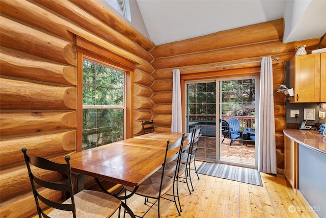 dining area featuring vaulted ceiling, log walls, and light hardwood / wood-style floors