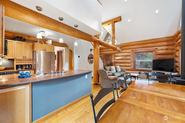 kitchen with rustic walls, sink, decorative light fixtures, light brown cabinets, and stainless steel refrigerator