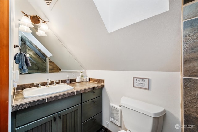 bathroom featuring vanity, lofted ceiling, and toilet