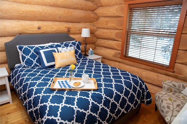 bedroom featuring log walls and hardwood / wood-style floors