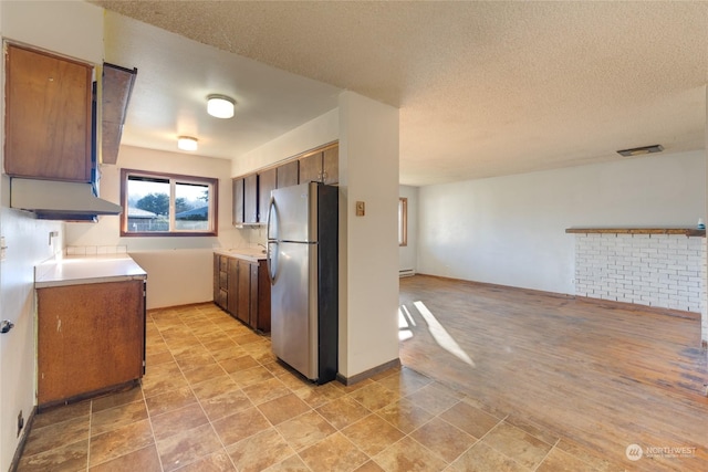 kitchen featuring a baseboard heating unit, stainless steel fridge, and a textured ceiling