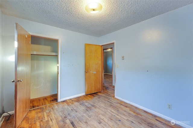 unfurnished bedroom with light hardwood / wood-style flooring, a textured ceiling, and a closet