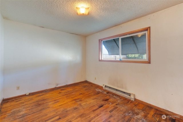 empty room with hardwood / wood-style flooring, a baseboard radiator, and a textured ceiling