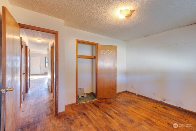 unfurnished bedroom with hardwood / wood-style flooring, a closet, and a textured ceiling