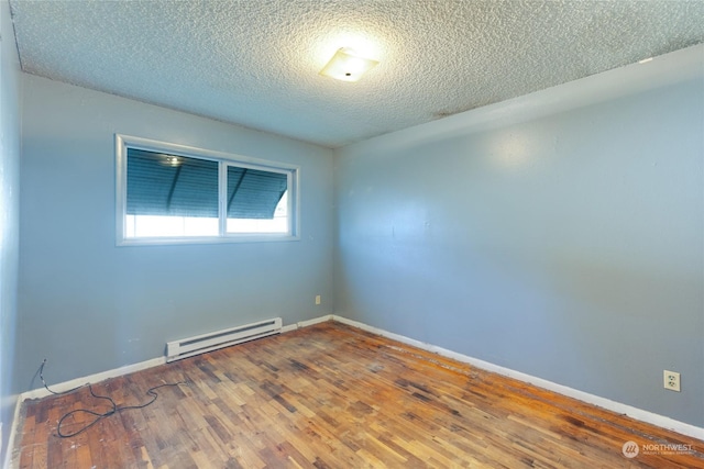 empty room with hardwood / wood-style flooring, a textured ceiling, and a baseboard heating unit