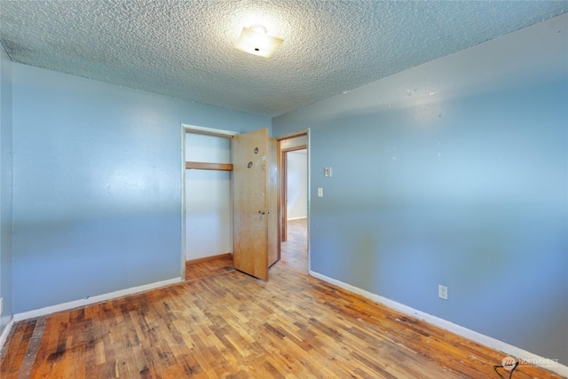 unfurnished bedroom featuring hardwood / wood-style floors, a textured ceiling, and a closet