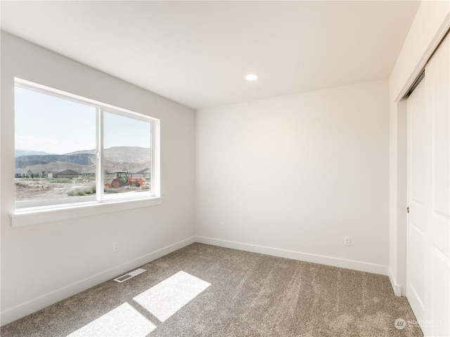 unfurnished bedroom featuring carpet flooring, a mountain view, and a closet