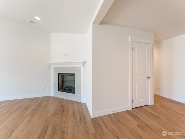 unfurnished living room with a tiled fireplace and light hardwood / wood-style floors