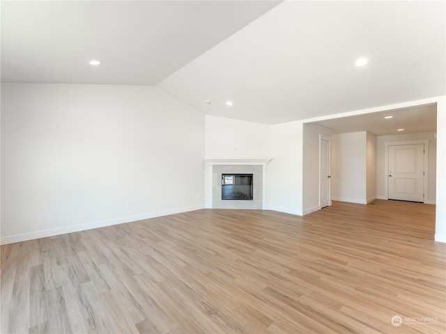 unfurnished living room featuring vaulted ceiling, a fireplace, and light hardwood / wood-style floors