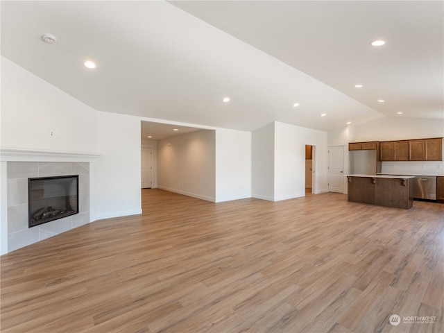 unfurnished living room with vaulted ceiling, a fireplace, and light hardwood / wood-style floors