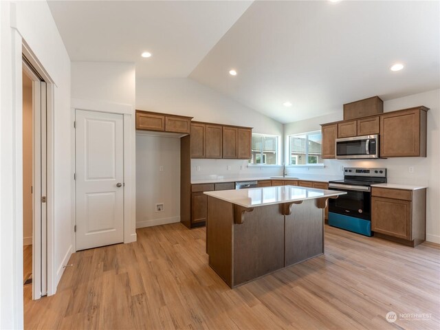 kitchen featuring a kitchen bar, sink, a center island, appliances with stainless steel finishes, and light hardwood / wood-style floors