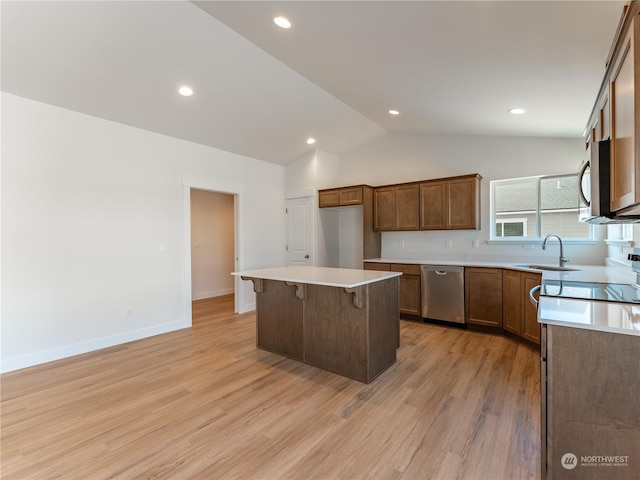 kitchen with a kitchen island, sink, a kitchen breakfast bar, stainless steel appliances, and light hardwood / wood-style flooring