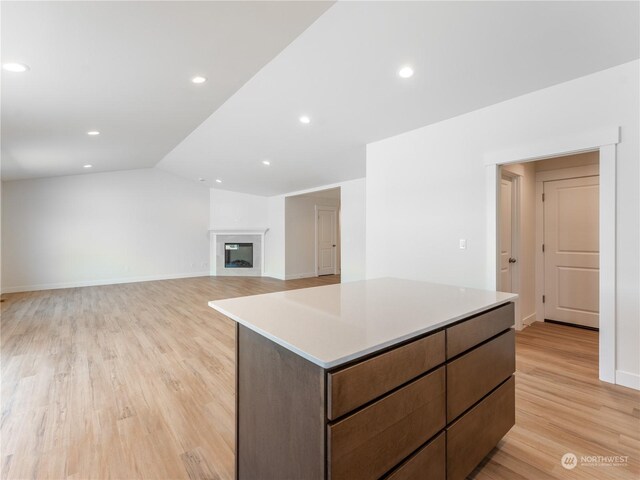 kitchen with vaulted ceiling, light hardwood / wood-style floors, and a kitchen island