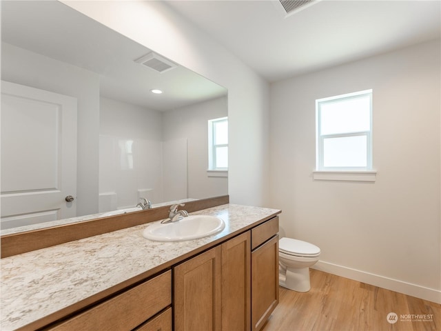 bathroom featuring vanity, hardwood / wood-style floors, toilet, and a healthy amount of sunlight