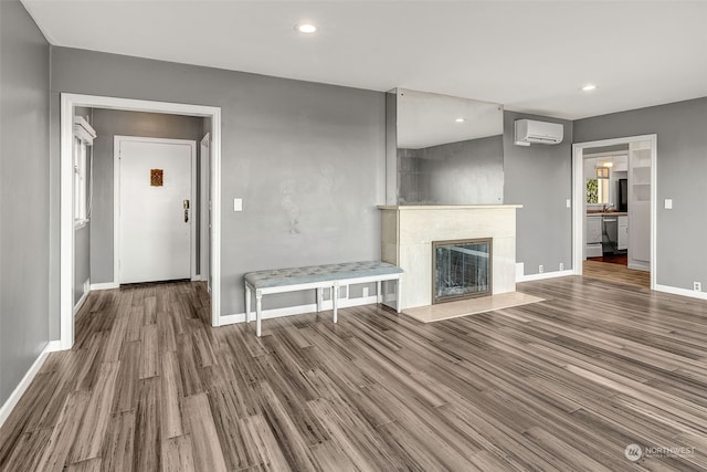 unfurnished living room with hardwood / wood-style flooring, a wall mounted AC, and a high end fireplace