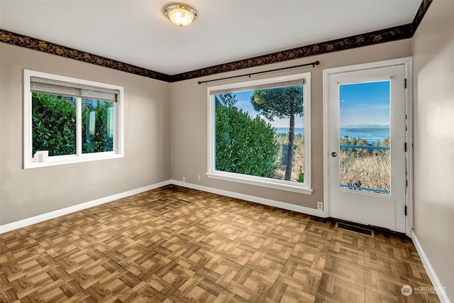 empty room with light parquet floors and a water view