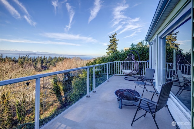 balcony featuring a water view and an outdoor fire pit