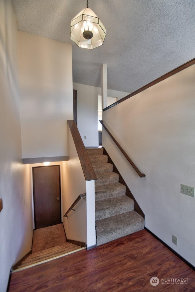 stairs featuring lofted ceiling, hardwood / wood-style flooring, and a textured ceiling