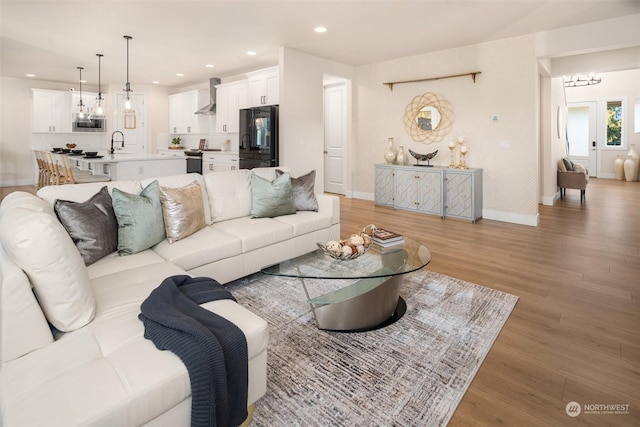 living room featuring sink, an inviting chandelier, and light hardwood / wood-style flooring