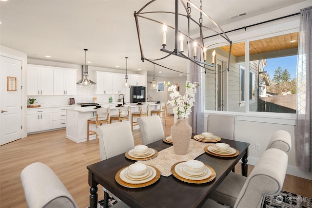 dining space featuring an inviting chandelier, sink, and light hardwood / wood-style floors