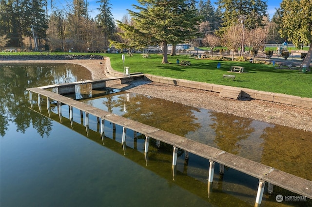 view of dock featuring a water view and a yard