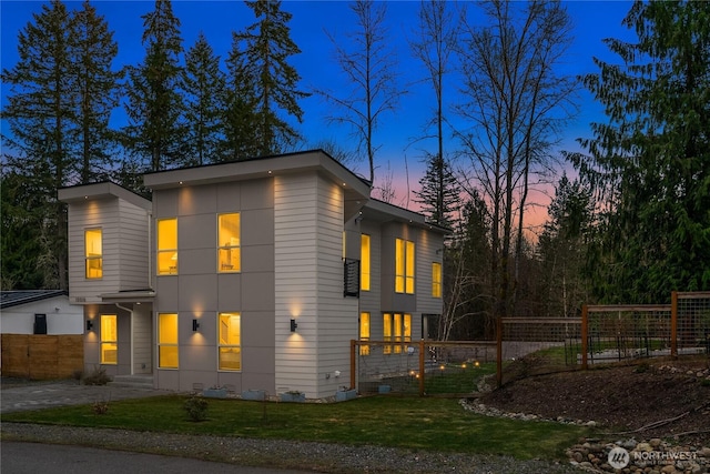 view of front facade with driveway, a front lawn, and fence