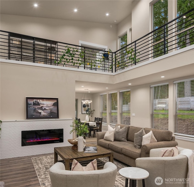 living area featuring wood finished floors, a glass covered fireplace, and recessed lighting