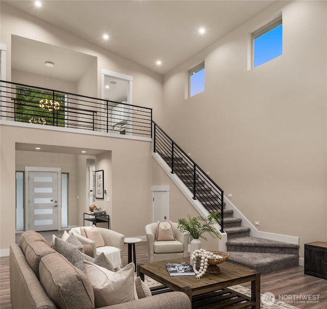 living area with baseboards, wood finished floors, a high ceiling, stairs, and recessed lighting