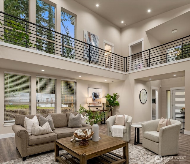 living area with a high ceiling, baseboards, wood finished floors, and recessed lighting