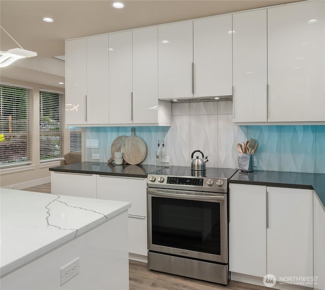 kitchen with recessed lighting, white cabinetry, light wood-style floors, stainless steel electric stove, and tasteful backsplash