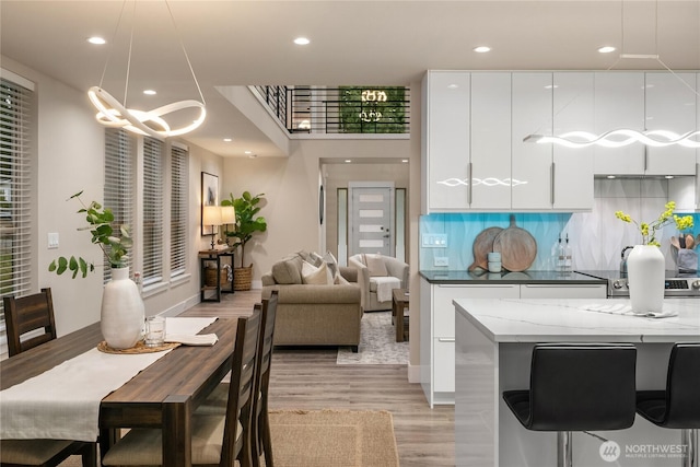 kitchen with tasteful backsplash, cooktop, light wood-style floors, white cabinetry, and modern cabinets