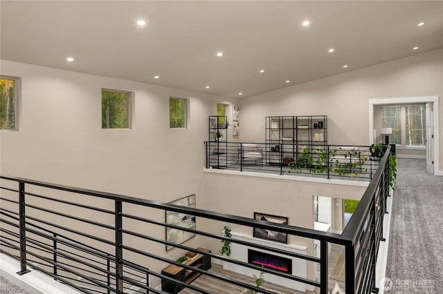 staircase with carpet, a glass covered fireplace, and recessed lighting