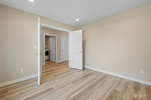 unfurnished bedroom featuring washer / dryer and light hardwood / wood-style flooring