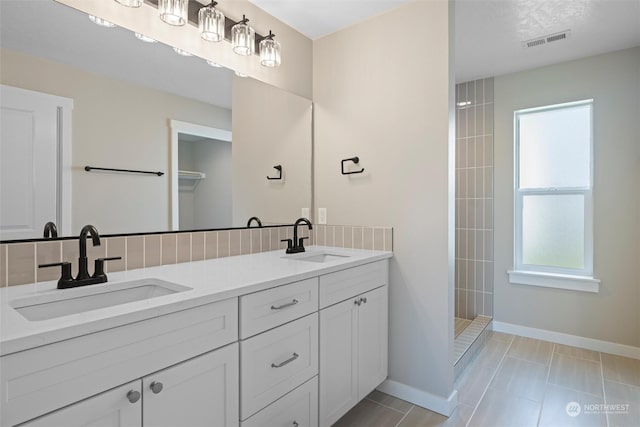 bathroom featuring tasteful backsplash, tile patterned floors, vanity, and walk in shower