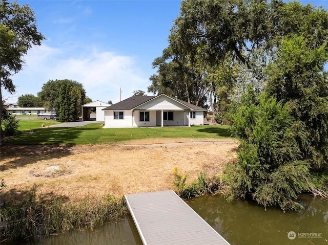 rear view of house featuring a water view and a yard