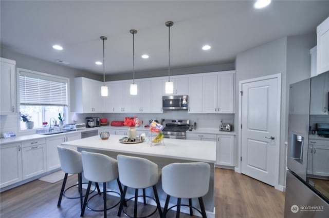 kitchen featuring hanging light fixtures, appliances with stainless steel finishes, white cabinets, and decorative backsplash