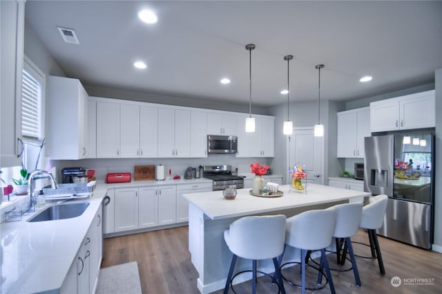 kitchen with sink, stainless steel appliances, a center island, white cabinets, and light wood-type flooring