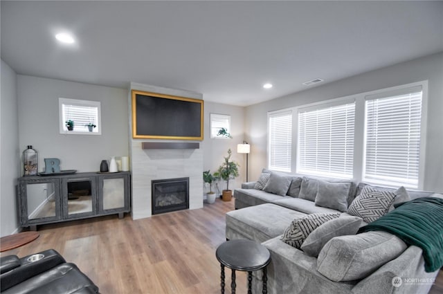 living room with a tile fireplace, plenty of natural light, and wood-type flooring