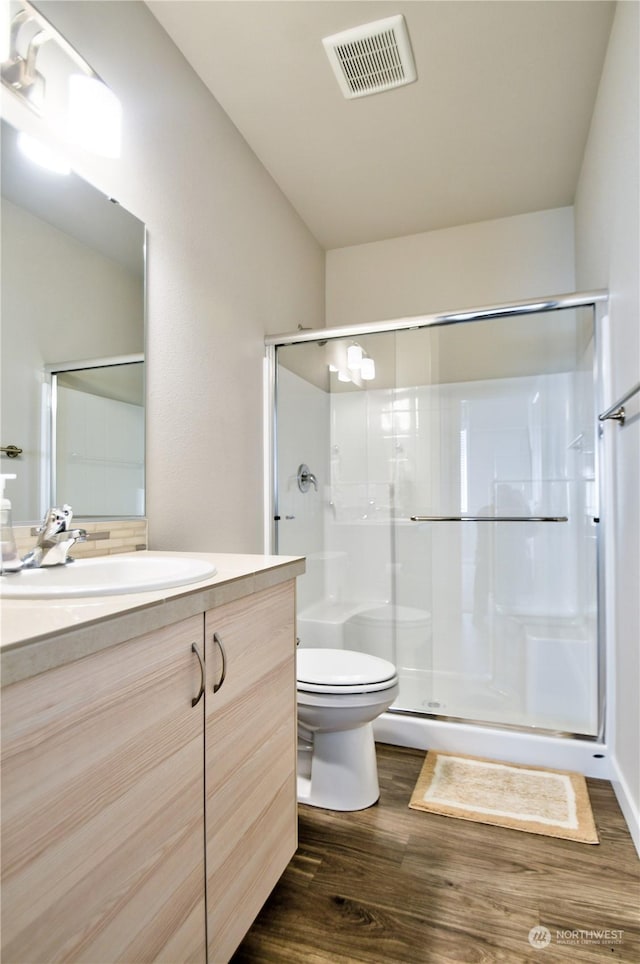 bathroom featuring an enclosed shower, vanity, wood-type flooring, and toilet