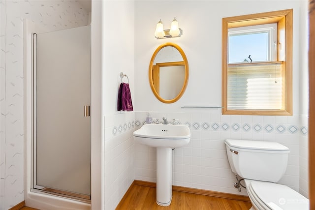 bathroom with toilet, a shower with shower door, sink, tile walls, and hardwood / wood-style flooring